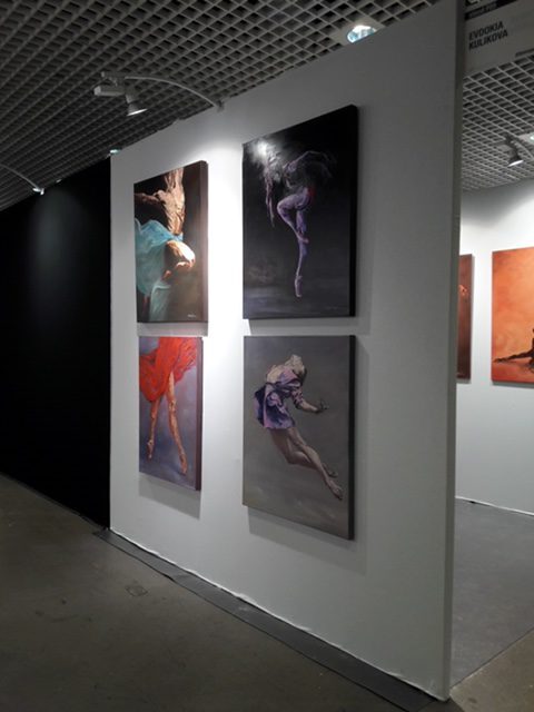 Ausstellungswand mit Tänzerinnen-Werken in rotem und blauem Licht
