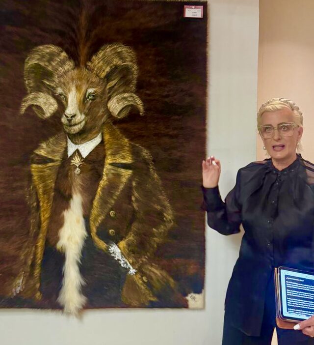 Evdokia Kulikova bei der Vernissage in Kitzbühel neben einem großformatigen Fellbild eines Widders im Anzug