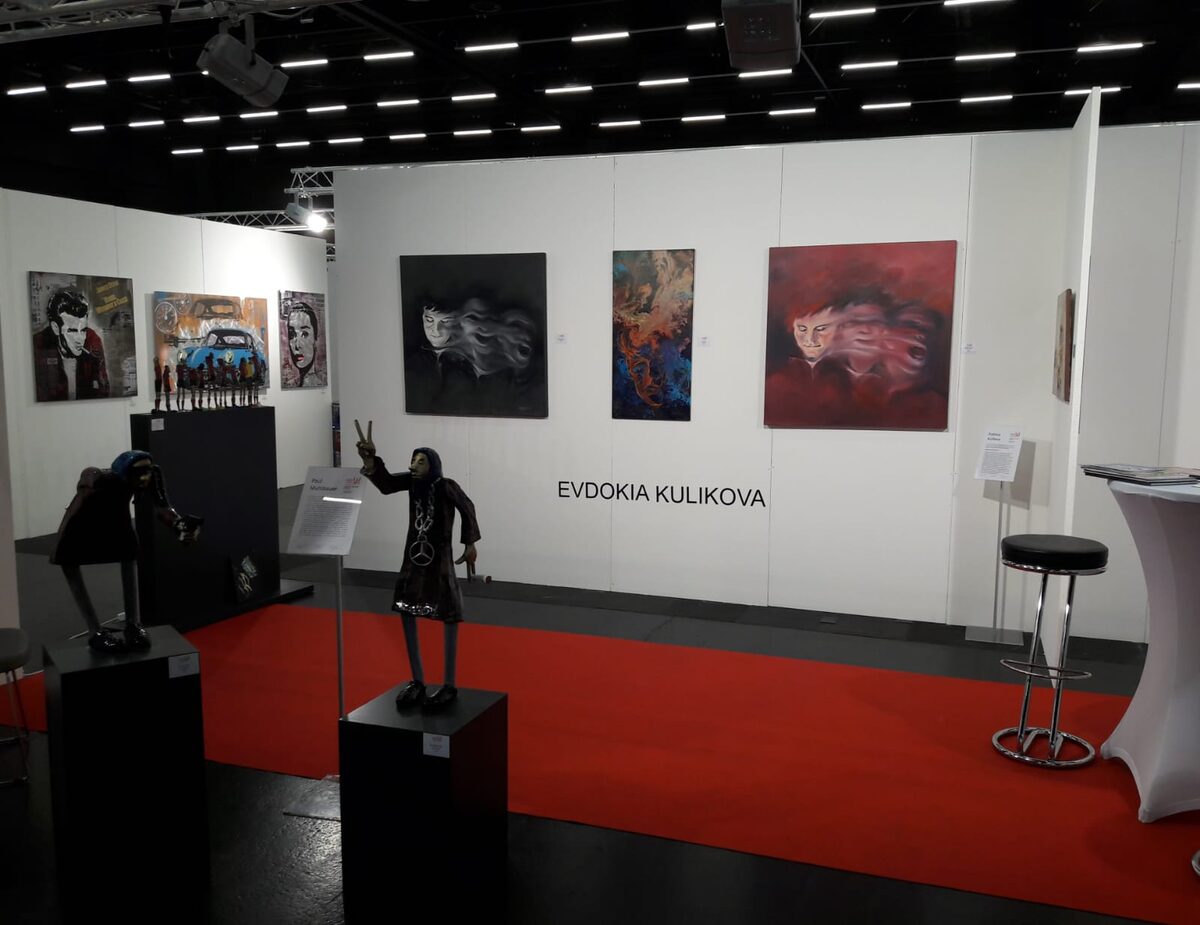 Messestand mit Schriftzug „Evdokia Kulikova“, Gemälden und Skulpturen auf rotem Teppich