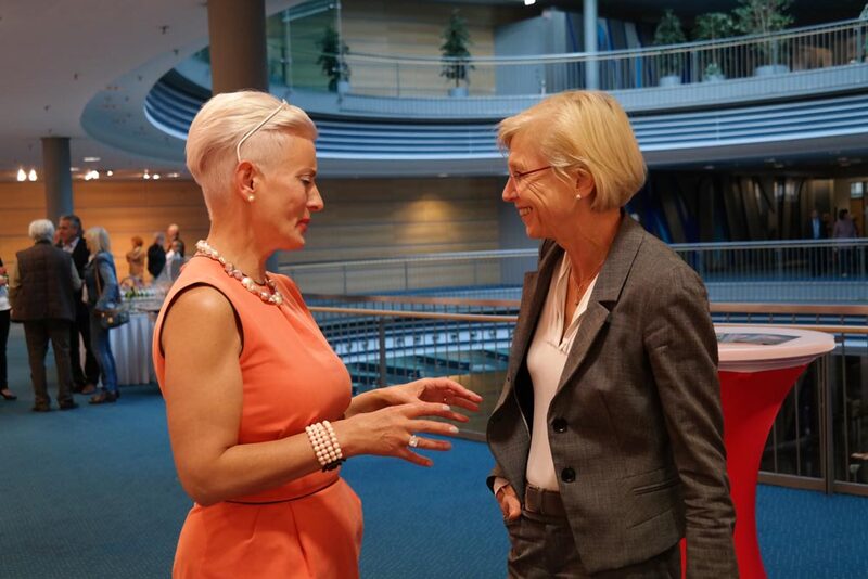 Zwei Frauen im Gespräch in einem blauen Foyer