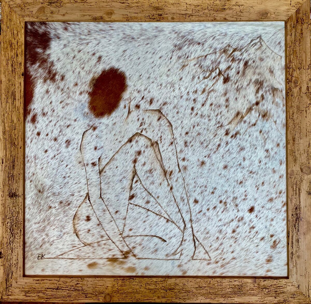 Sitzende Figur als Liniendarstellung auf gepunktetem Fell, im Holzrahmen
