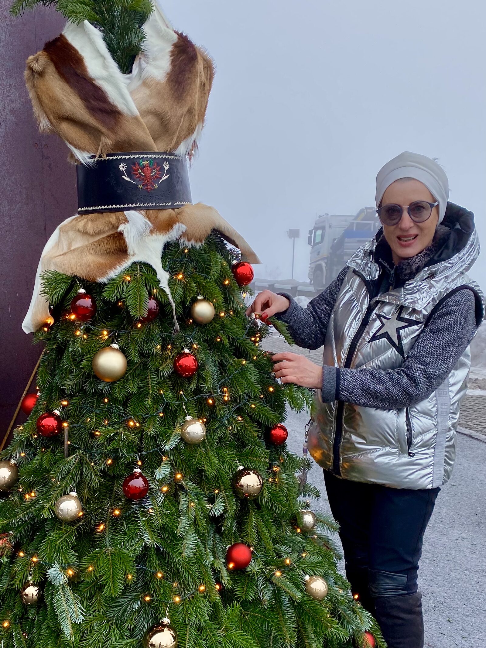 Die Künstlerin schmückt das Weihnachtsbaum-Kleid einer Puppenfigur im Freien