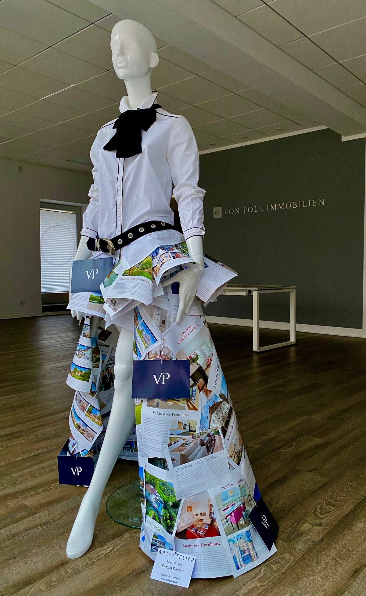 Schaufensterpuppe in einem Kleid aus Zeitungsseiten und Fotografien