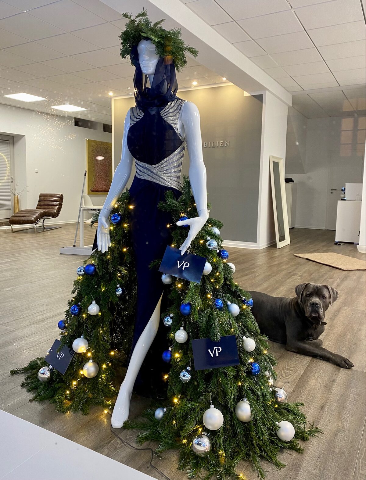 Weihnachtsbaum-Kleid an einer Puppe im Ausstellungsraum, daneben ein Hund