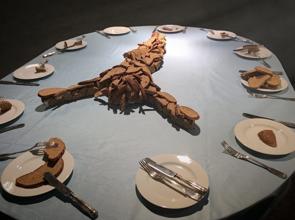 Runder gedeckter Tisch mit kreuzförmiger Brot-Skulptur, Installationsansicht von der Seite