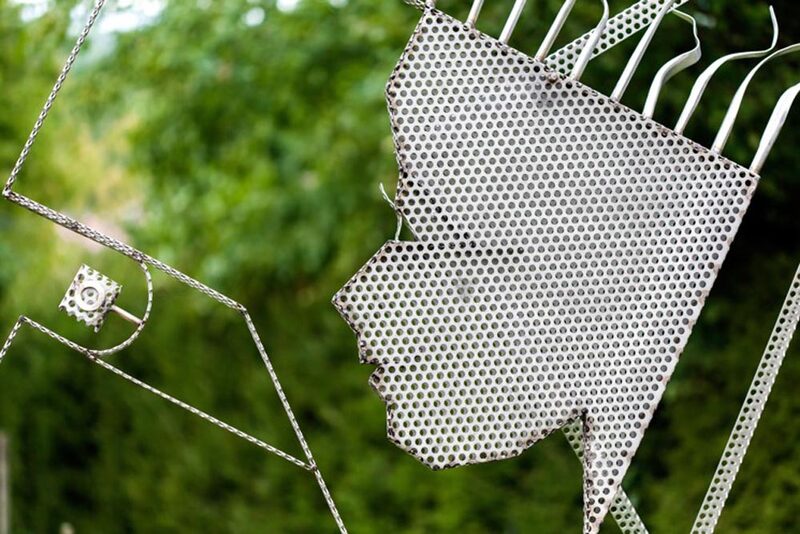 Gesichtssilhouette aus Metallgewebe vor grünem Garten
