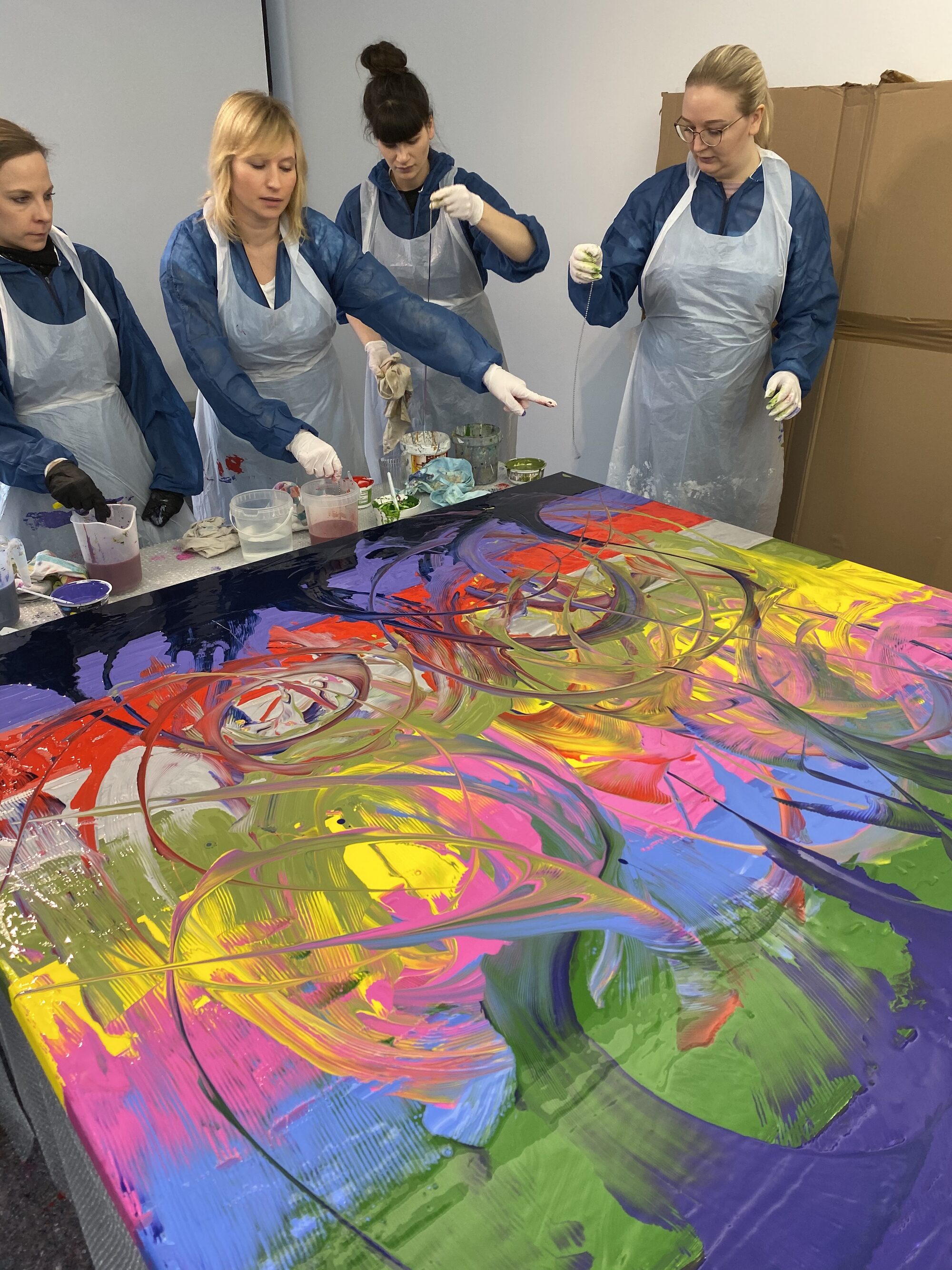 Gruppe beim Workshop rund um ein großformatiges, farbenfrohes Fluid-Art-Bild