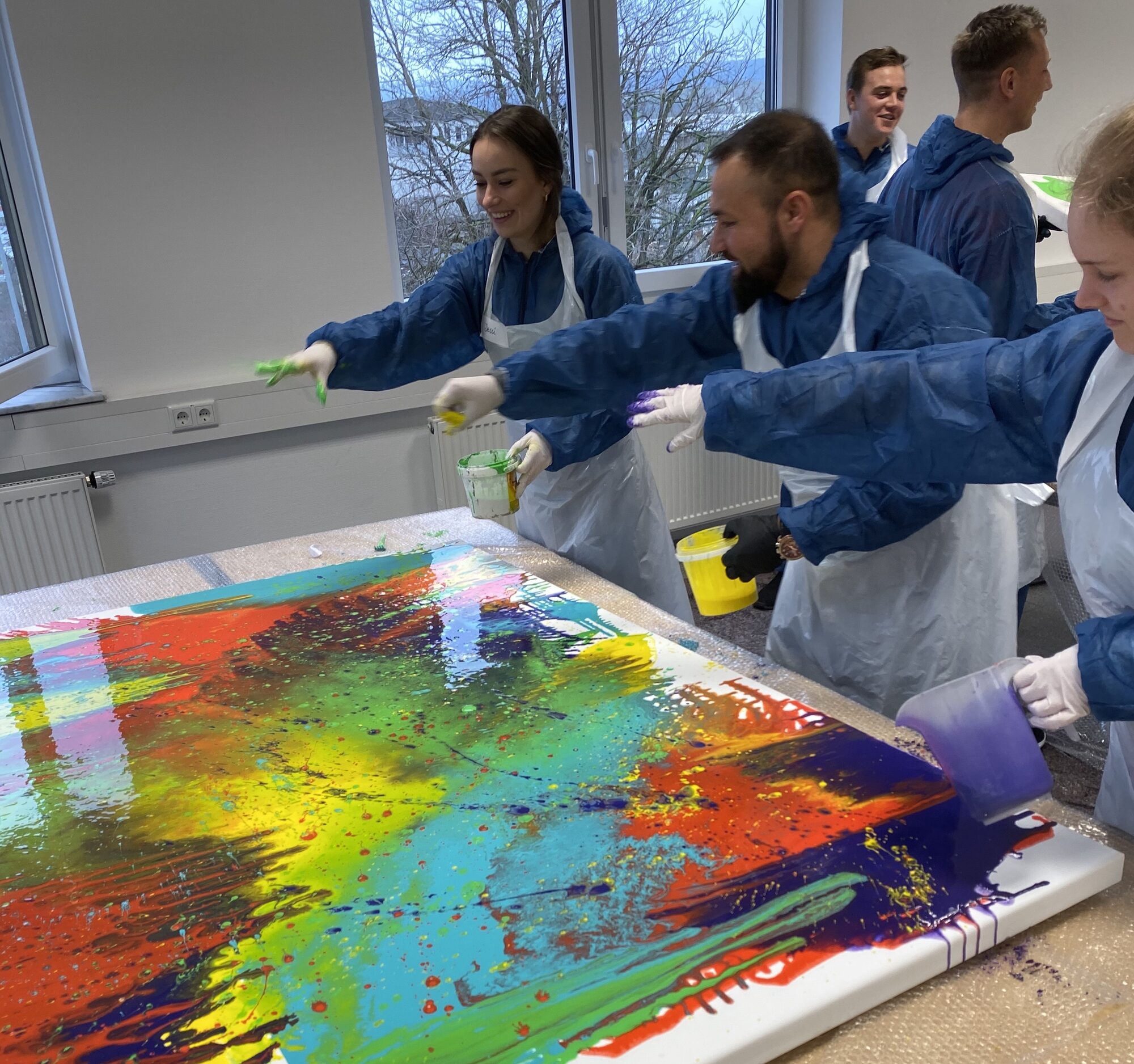 Teilnehmende verteilen leuchtende Farben auf einer Leinwand